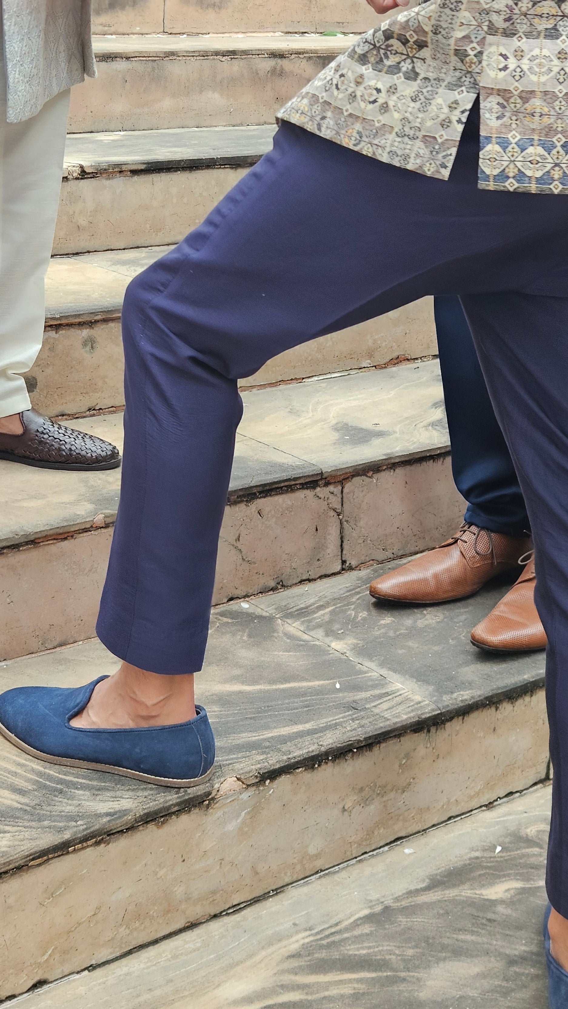 Person wearing a navy suit and blue shoes on a wooden floor.